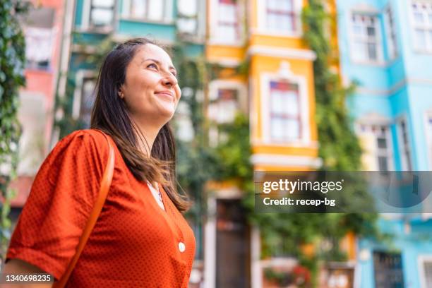 portrait of beautiful woman in front of colorful buildings in city - multi colored dress bildbanksfoton och bilder