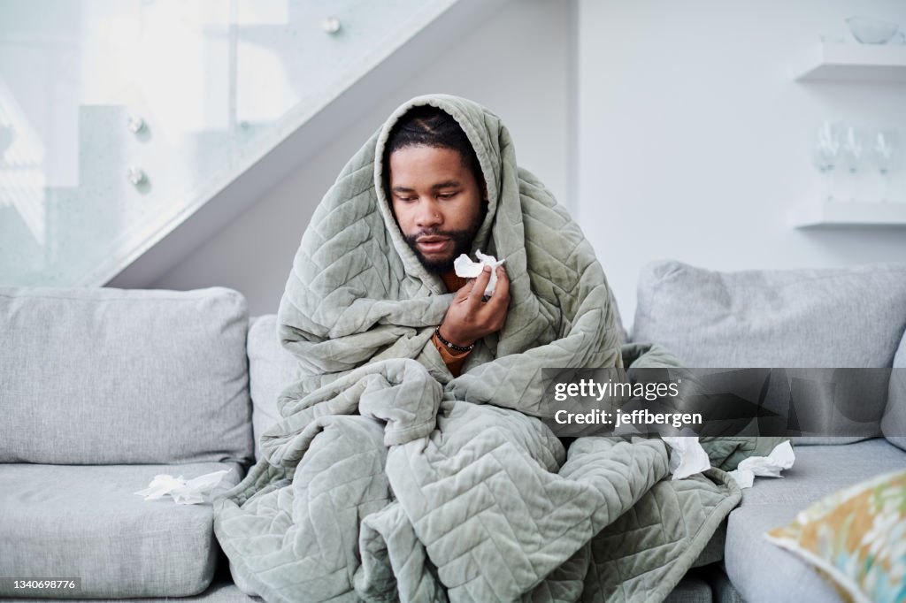 Photo d’un jeune homme atteint de la grippe assis sur le canapé à la maison