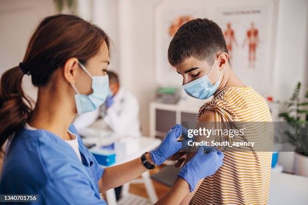 nurse putting band aid on patient's arm after covid-19 vaccination - shot stockfoto's en -beelden