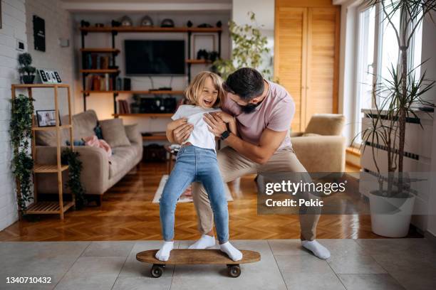 father teaching his daughter how to skateboard - indoor skating stock pictures, royalty-free photos & images