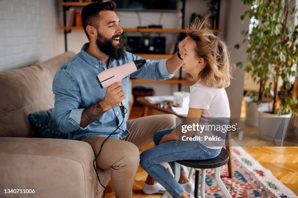 young bearded single father drying his daughters hair in domestic room - beautiful hair at home stock pictures, royalty-free photos & images