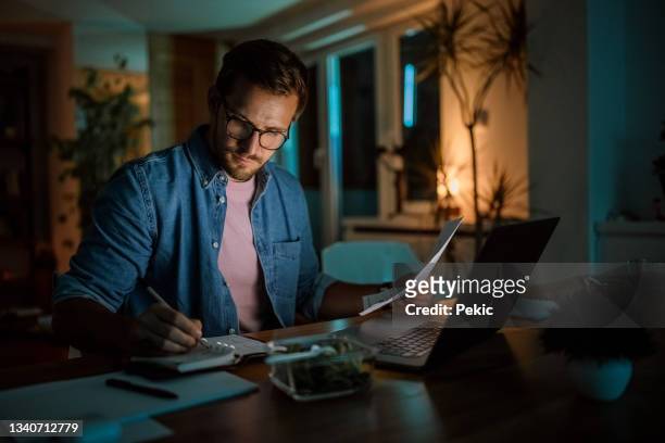 serious handsome man working late from his home office - home office stock pictures, royalty-free photos & images