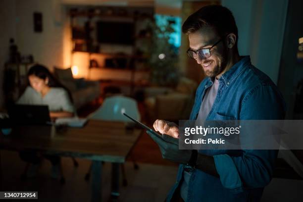smiling man using digital tablet late night - man business hipster dark smile stock pictures, royalty-free photos & images