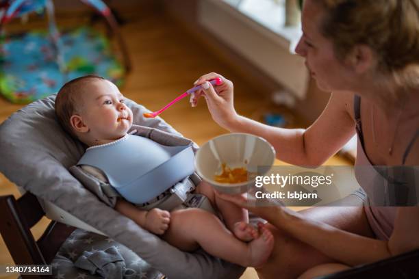 mother feeding her smiling baby boy. - baby eating toy stock pictures, royalty-free photos & images