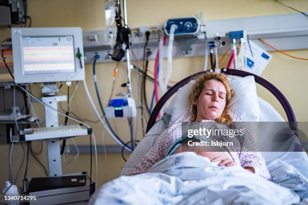 mother labours in hospital bed during childbirth. - delivery room stock pictures, royalty-free photos & images