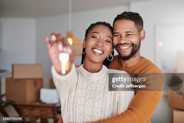 foto de una joven pareja abrazándose mientras muestra las llaves de su nueva casa en casa - homeowner fotografías e imágenes de stock