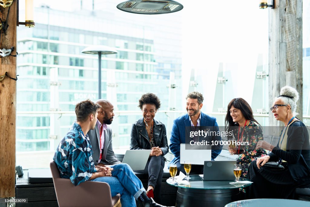 Group of multi racial business colleagues talking after conference, friendly and relaxed atmosphere, after conference drinks