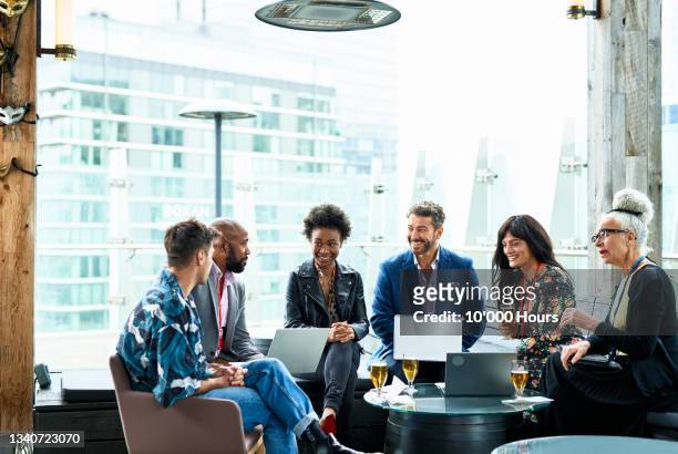 group of multi racial business colleagues talking after conference, friendly and relaxed atmosphere, after conference drinks - enterprise imagens e fotografias de stock
