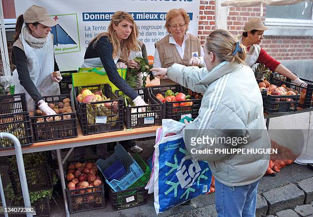 Une bénévole de l'association "La Tente des Glâneurs" distribue gratuitement un sac de fruits et légumes invendus à une femme, le 20 novembre 2011 à...