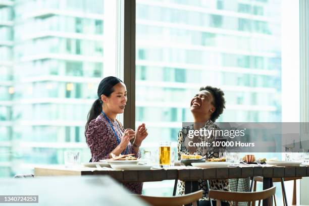 two female colleagues with drinks in bar, black woman laughing - conference hotel stock pictures, royalty-free photos & images