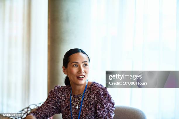 portrait of chinese businesswoman smiling and looking away - portrait bureau photos et images de collection