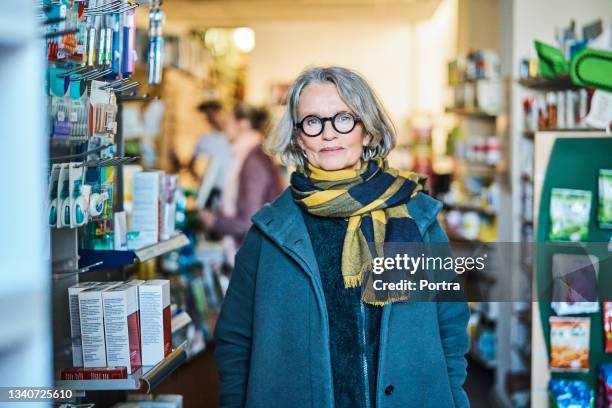 female customer standing in drugstore - pharmacy customer stock pictures, royalty-free photos & images