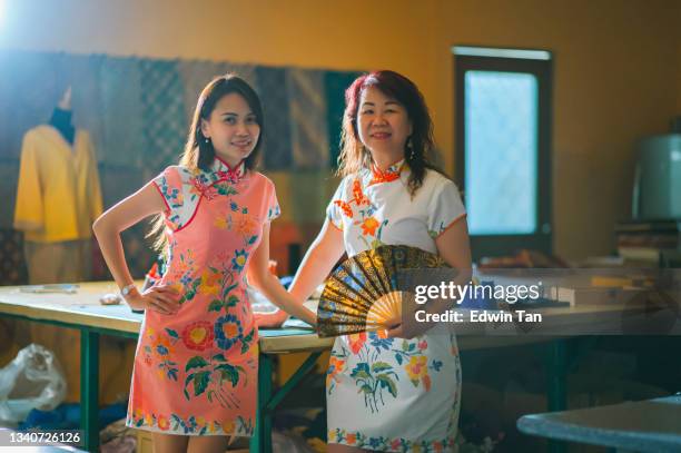 asian chinese female tailor small business owner and her mother standing at work place with chinese tradition clothing cheongsam holding folding fan hands on chin smiling with confidence and satisfaction looking at camera - the cheongsam stock pictures, royalty-free photos & images