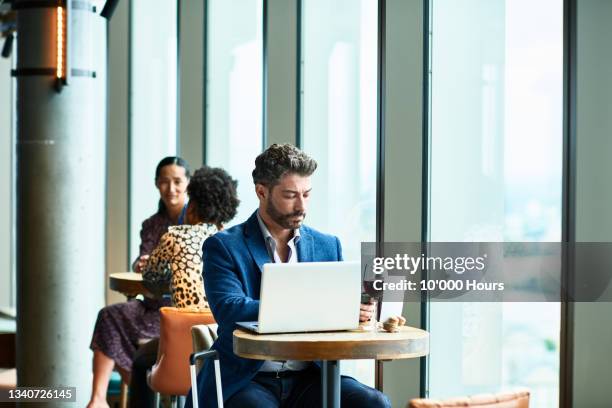 mature businessman using laptop in conference centre bar - wine glasses stock pictures, royalty-free photos & images