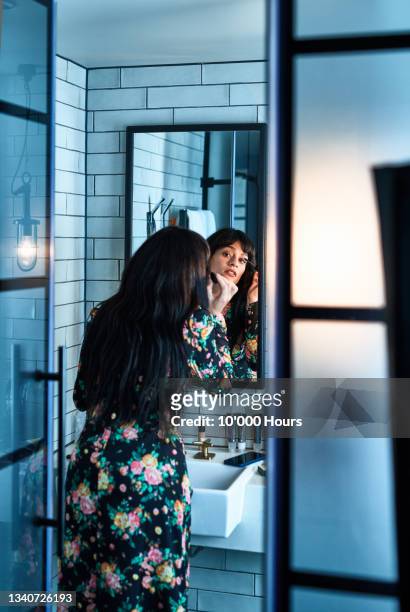 young woman applying mascara in vintage bathroom - woman mirror dress stock-fotos und bilder