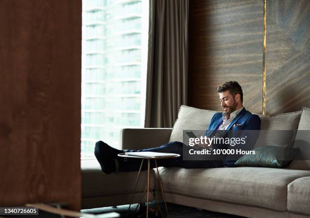 mature businessman texting on phone in hotel room - luxury hotel fotografías e imágenes de stock