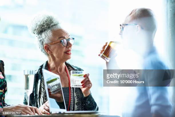 senior woman enjoying drink with mid adult man at business conference - gin tónico - fotografias e filmes do acervo