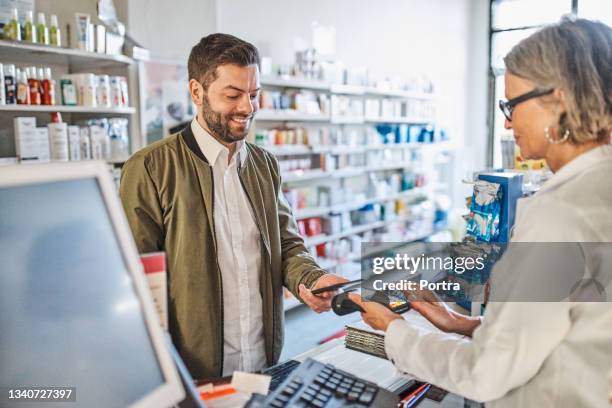man paying at checkout counter in pharmacy store - convenient store 個照片及圖片檔