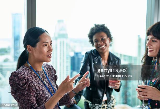 chinese woman explaining to colleagues over after work drinks - after work stock pictures, royalty-free photos & images