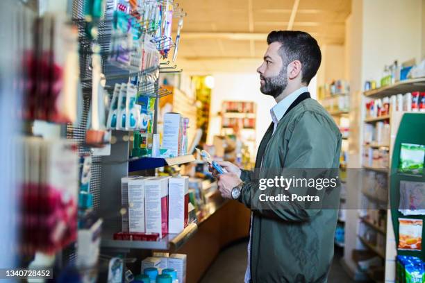 homme achetant une brosse à dents à la pharmacie - fourniture médicale photos et images de collection