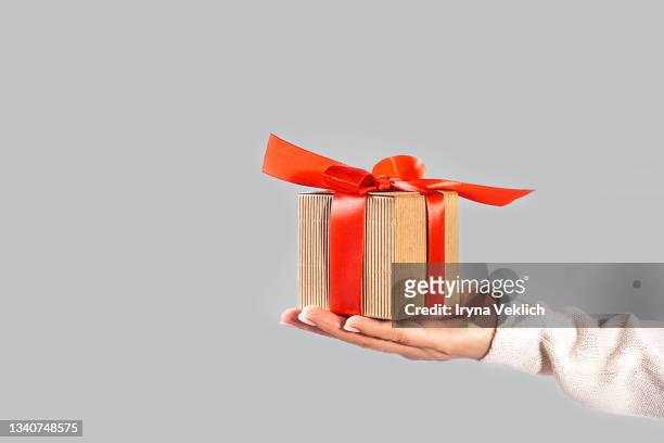 woman's hand with christmas gift box on  gray color background. - gift hand stock pictures, royalty-free photos & images