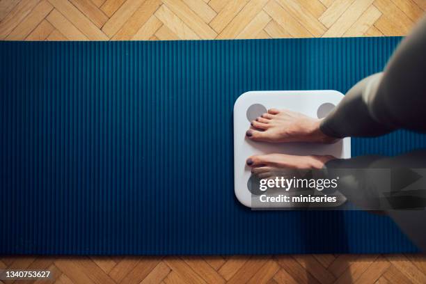 unrecognizable fitness woman measuring weight with scale - weegschaal stockfoto's en -beelden