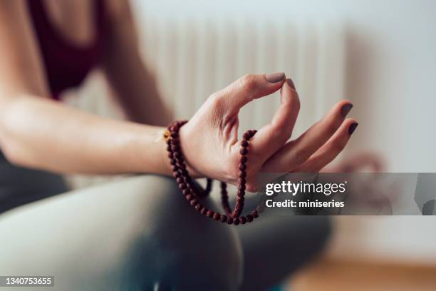 hand der frau, die mala-perlen hält und zu hause meditiert - gebetskette stock-fotos und bilder