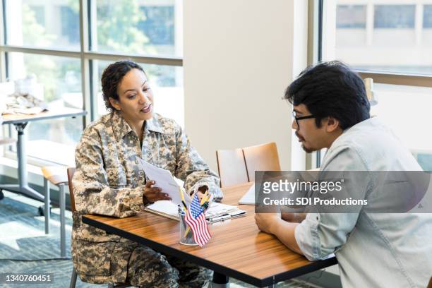female soldier explains documents to mid adult man - military recruitment stock pictures, royalty-free photos & images