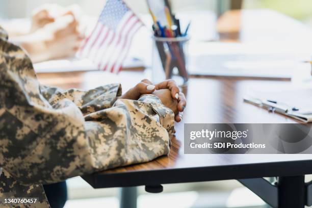 close up of unrecognizable female soldier's clasped hands - veteran stock pictures, royalty-free photos & images