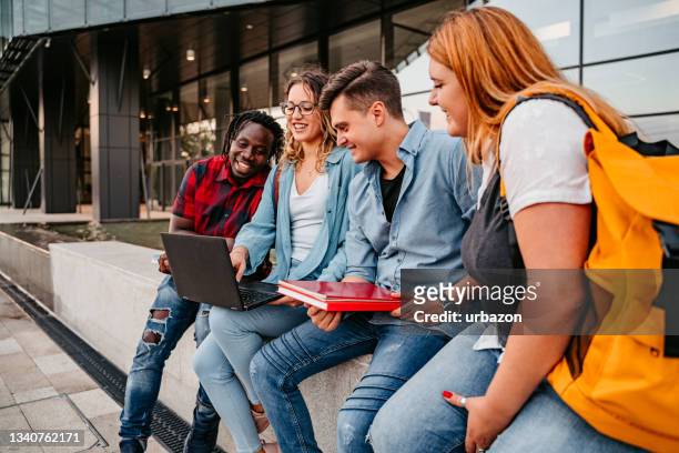 happy college friends using laptop while studying on break - african creative with laptop working outside stockfoto's en -beelden