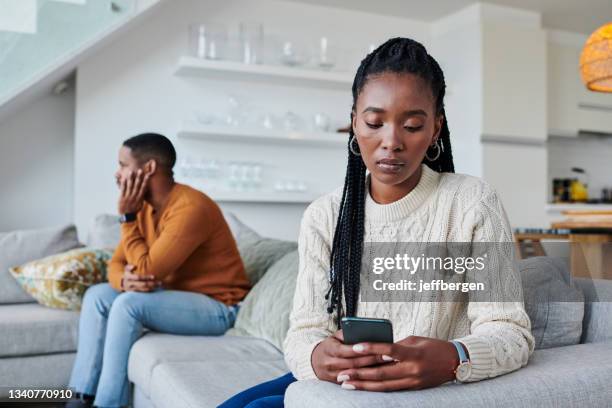 foto de una joven ignorando a su pareja mientras usaba un teléfono celular en casa - man looking upset fotografías e imágenes de stock