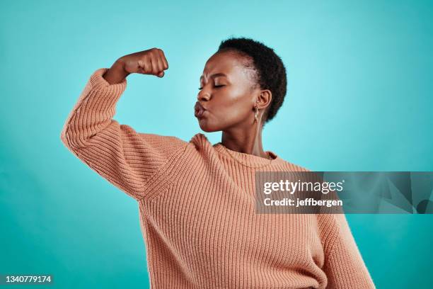 shot of a beautiful young woman flexing while standing against a turquoise background - proud bildbanksfoton och bilder