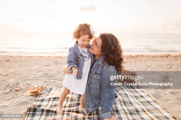 a 30-year-old mother & 2-year-old daughter enjoying a quiet golden beach sunrise in palm beach, florida in september of 2021 - beach florida family stockfoto's en -beelden