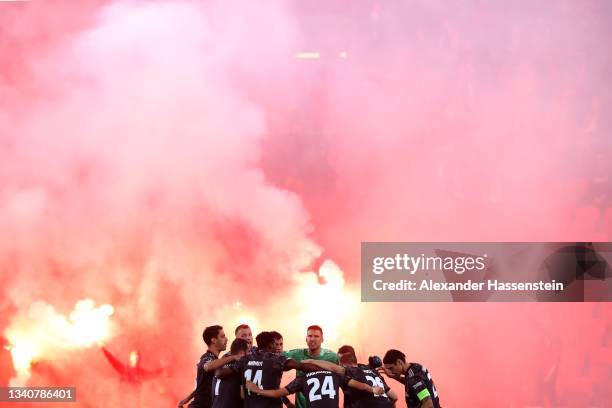 Players of Union Berlin gather as flares are seen being set off by fans prior to the UEFA Europa Conference League group E match between Slavia Praha...