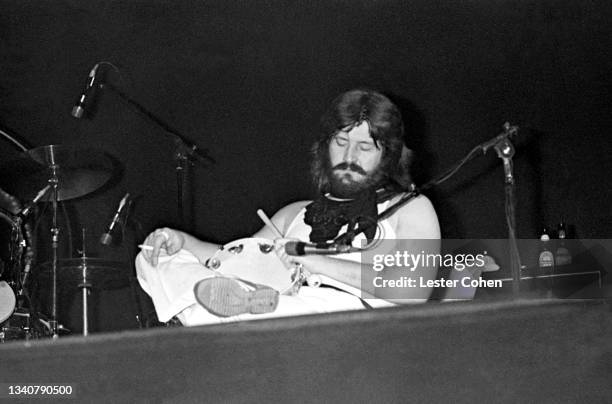 English drummer and songwriter John Bonham , of the English rock band Led Zeppelin, holds a cigarette and the tambourine while sitting on stage...