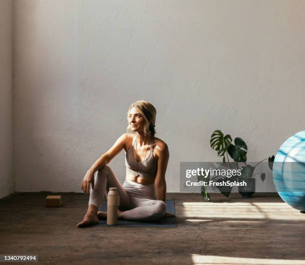una joven rubia caucásica sentada en una esterilla de yoga - yoga ball fotografías e imágenes de stock