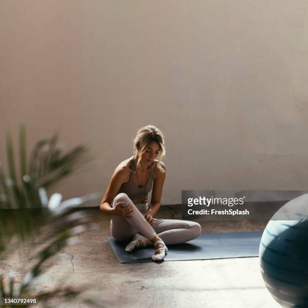 eine junge blonde kaukasische frau, die drinnen auf ihrer matte yoga macht - skinny blonde pics stock-fotos und bilder