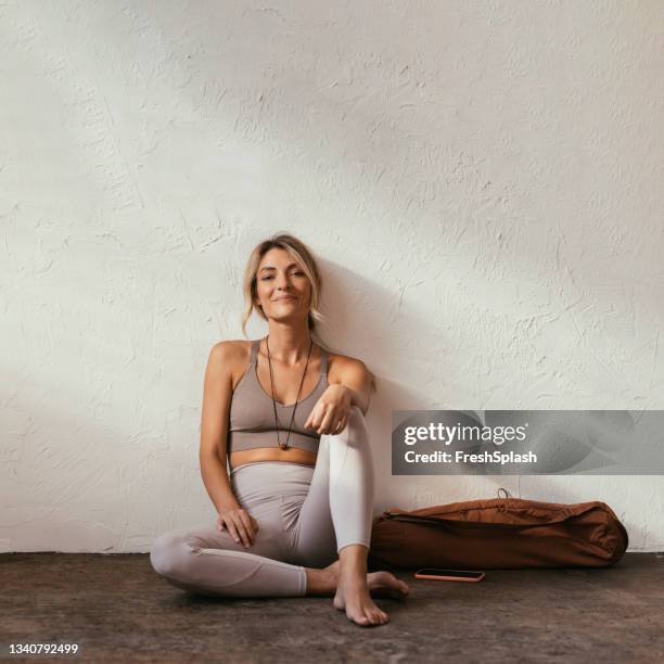 una joven rubia caucásica sentada y sonriendo en ropa deportiva - leggings fotografías e imágenes de stock