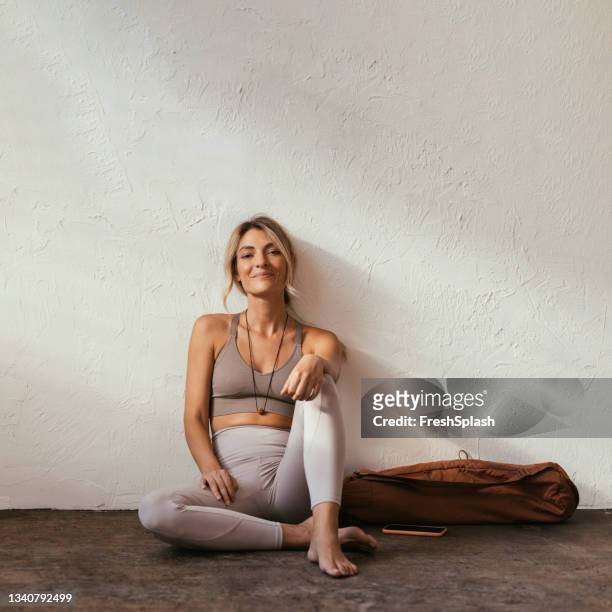 a young blonde caucasian woman sitting and smiling in sportswear - leggings 個照片及圖片檔