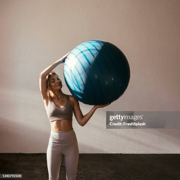 una joven rubia caucásica sosteniendo una pelota de yoga - yoga ball fotografías e imágenes de stock