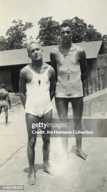 Black-and-white film photo shows two men in one-piece bathing suits in a posed portrait with hands behind their backs, circa 1931.