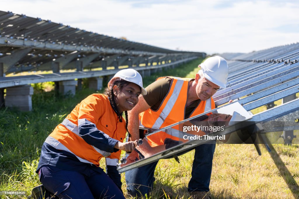 Senior Engineer and Aboriginal Australian Apprentice Working Together On Solar Farm Installation