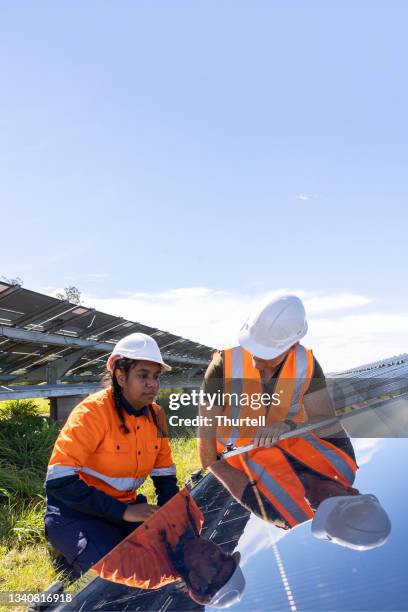 senior engineer and aboriginal australian apprentice working together on solar farm installation - solar power station stock pictures, royalty-free photos & images