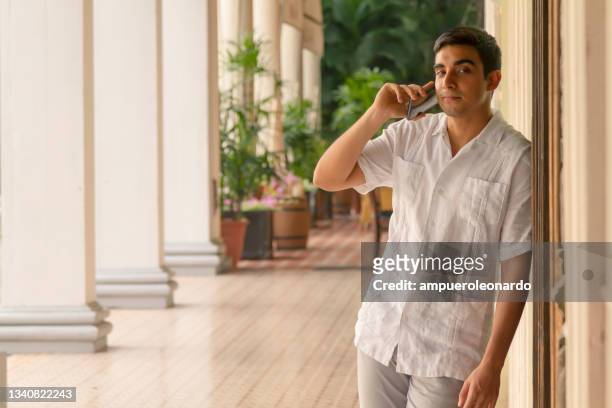 young latin male portrait, traveling and talking by smartphone / cellphone using 5g technology at guayaquil old downtown, guayas, ecuador, latin america - ecuadorian ethnicity stock pictures, royalty-free photos & images