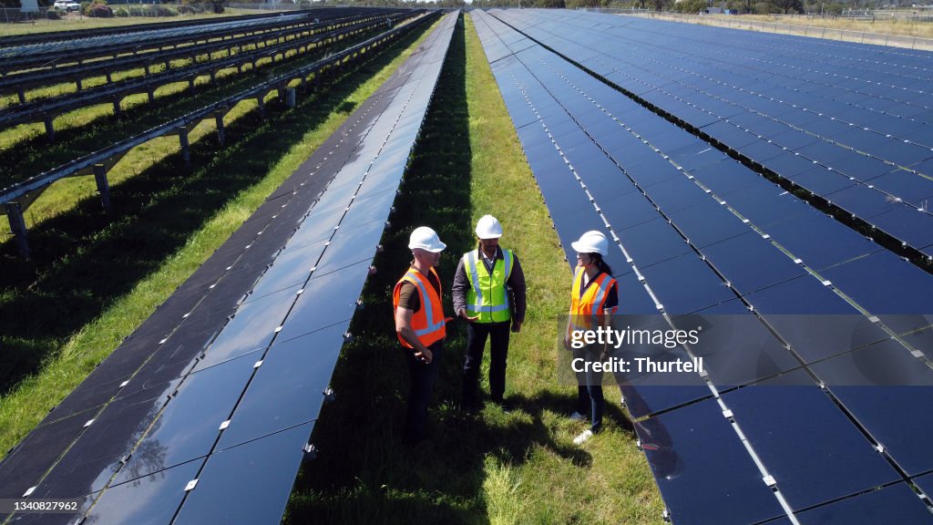 Multiracial Group Of Three Engineers Surrounded By Solar Panels
