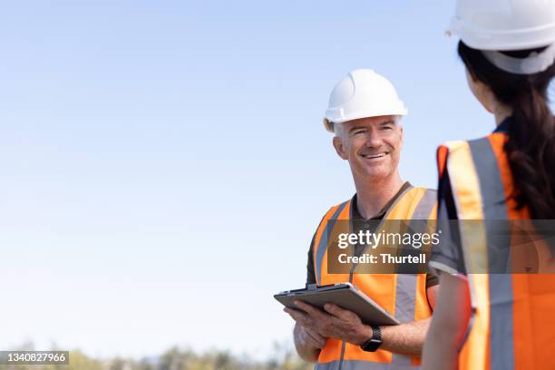 ingenieros que trabajan juntos en la instalación de granjas solares - material reflector de seguridad fotografías e imágenes de stock