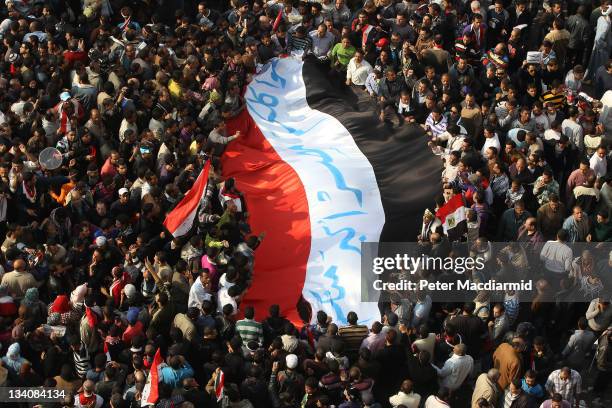Protestors carry a giant Egyptian flag in Tahrir Square during a mass rally on November 25, 2011 in Cairo, Egypt. Thousands of Egyptians are...