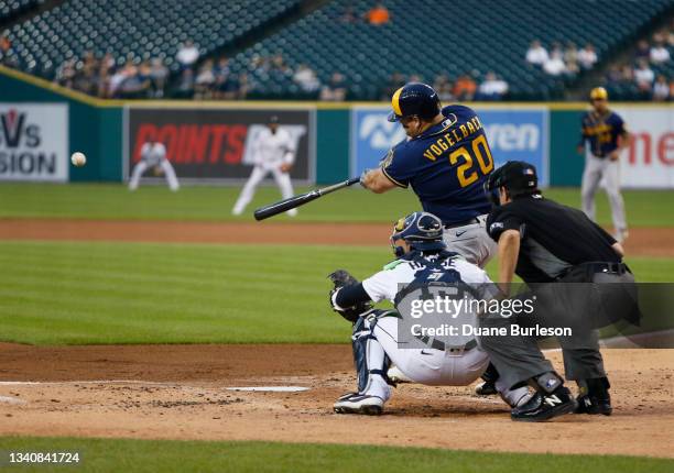 Daniel Vogelbach of the Milwaukee Brewers hits a fly ball with catcher Eric Haase of the Detroit Tigers behind the plate with umpire Doug Eddings...