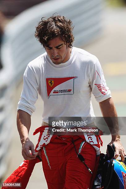 Fernando Alonso of Spain and Ferrari walks back to the pits after retiring early with an engine problem during practice for the Brazilian Formula One...