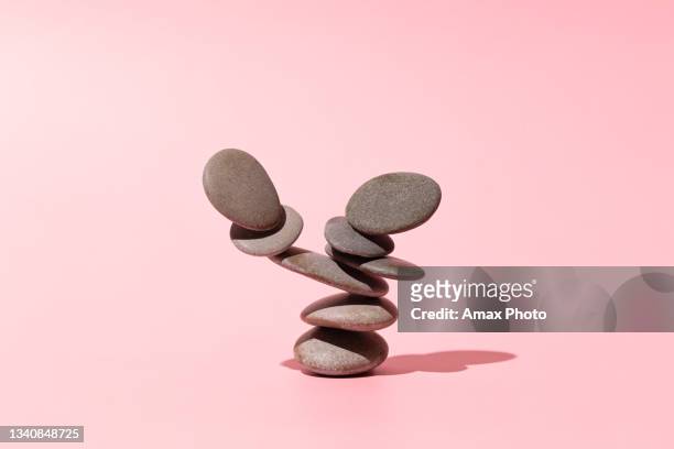concept of balance of gray stones on a pink background - men balancing stockfoto's en -beelden